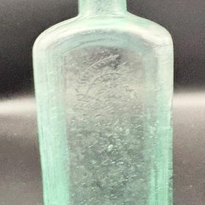 Antique Embossed aqua glass patent medicine bottle by Healy & Bigelow.