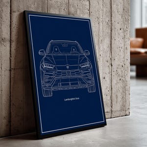 May include: A framed print featuring a white line drawing of a Lamborghini Urus SUV against a dark blue background. The text "Lamborghini Urus" is at the bottom. The frame is black.