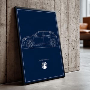 May include: A framed blueprint-style illustration of a Vauxhall Corsa GS car in white lines on a dark blue background. The car is depicted in profile, with the Vauxhall logo and model name at the bottom. The frame is black, leaning against a concrete wall.