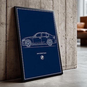 May include: A framed print with a dark blue background, displaying a white line drawing of a BMW 320d M Sport. The car's outline is detailed, showing wheels and body contours. The BMW logo is at the bottom of the print.