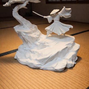 Peut inclure: Sculpture blanche représentant un samouraï en action, tenant une épée, sur un socle rocheux avec un bonsaï. La figurine est détaillée, avec des vêtements fluides et un chapeau. La sculpture est posée sur un tatami.