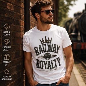 Op de afbeelding: Wit T-shirt met de tekst "RAILWAY ROYALTY" in een zwart vintage ontwerp. De afbeelding bevat een kroon en een treinwiel. Het shirt met korte mouwen lijkt van een zacht materiaal te zijn.