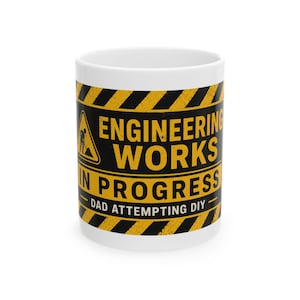 May include: White ceramic mug with a black and yellow design. The mug features the text "ENGINEERING WORKS IN PROGRESS" and "DAD ATTEMPTING DIY". A construction worker icon is also present.