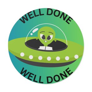 May include: A circular sticker with a green and teal gradient background featuring a cartoon alien in a lime green flying saucer. The alien has large black eyes and a white suit. The text WELL DONE is printed in black at the top and bottom.