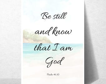 May include: A rectangular wall art print featuring a watercolor landscape of a beach and ocean with the black text "Be still and know that I am God" and "Psalm 46:10" printed in a cursive font centered over the light blue and tan scenery.