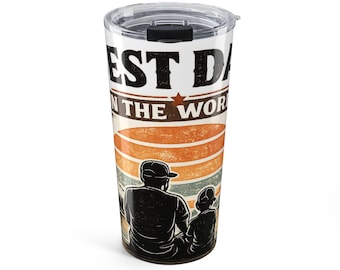Op de afbeelding: Een cilindervormige roestvrijstalen beker met een doorzichtig plastic deksel. De buitenkant toont een afbeelding van een zonsondergang achter het silhouet van twee personen met petten, met de tekst BEST DAD IN THE WORLD in zwart en oranje.