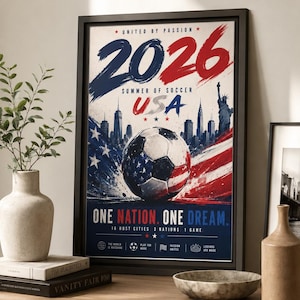 Puede incluir: Un p&oacute;ster enmarcado para el Summer of Soccer 2026 en EE. UU. El dise&ntilde;o presenta un bal&oacute;n de f&uacute;tbol con un patr&oacute;n de bandera estadounidense, un horizonte urbano con la Estatua de la Libertad y el texto 2026, USA, One Nation. One Dream.