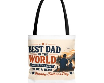 Op de afbeelding: Een witte tote bag met zwarte hengsels voorzien van een afbeelding van een persoon en een kind die bij zonsondergang op een steiger zitten. De tekst luidt: BEST DAD IN THE WORLD, NO NEED FOR A CAPE TO BE A HERO en Happy Father's Day.