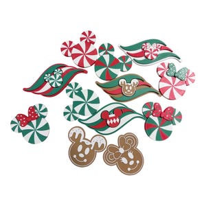 May include: A collection of decorative cutouts featuring holiday-themed shapes including peppermint swirls, gingerbread-style character heads, and wavy ribbons in red, green, white, and brown. The pieces include various circular and character-inspired designs.