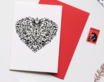 May include: A white card with a black and white intricate heart design. The card is blank and ready for a message.