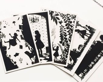 May include: Set of five black and white postcards featuring silhouettes of Alice in Wonderland characters. The postcards feature scenes from the book, such as Alice falling down the rabbit hole, the Mad Hatter's tea party, and the Queen of Hearts' croquet game. The text "Alice's Adventures in Wonderland" is printed on a separate card.