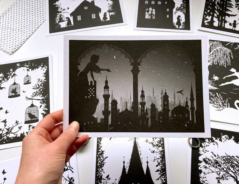 May include: A black and white silhouette print of a woman standing on a balcony overlooking a city skyline. The woman is reaching out with her hand, as if to touch the stars in the night sky. The city is filled with tall buildings and minarets, and the sky is filled with stars.