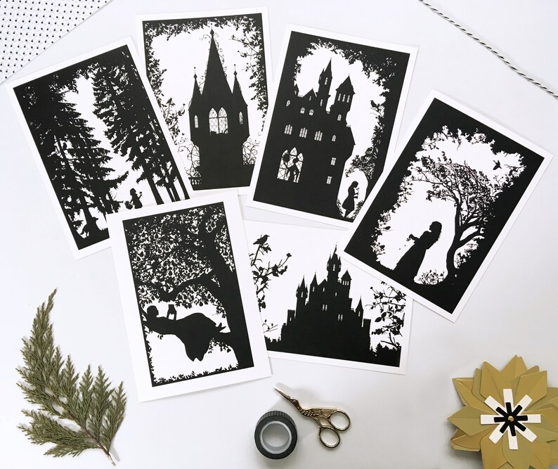May include: Set of six black and white silhouette prints featuring a castle, a forest, a tree, and a girl reading a book. The prints are on white cardstock and have a simple, elegant design.