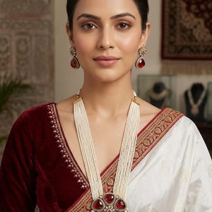 May include: A long multi-strand pearl necklace featuring a large circular pendant with six teardrop-shaped red stones and a central cluster of small white stones, paired with matching teardrop-shaped red stone earrings set in a metallic frame.