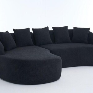May include: A contemporary black sectional sofa with a curved design. The sofa has a textured fabric and includes five matching square throw cushions. The furniture is set against a white background.