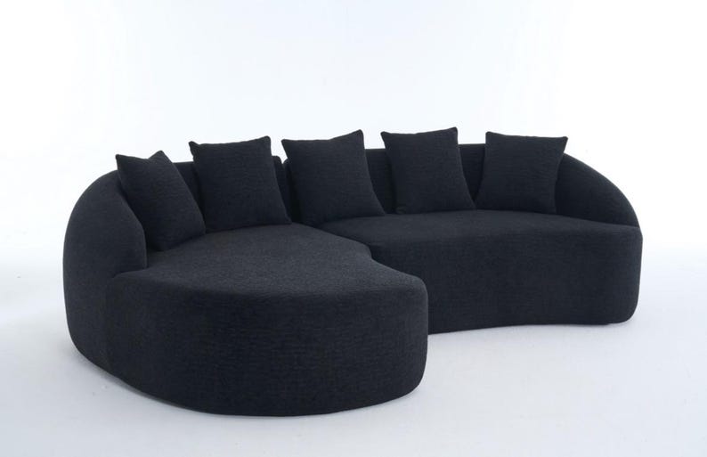 May include: A contemporary black sectional sofa with a curved design. The sofa has a textured fabric and includes five matching square throw cushions. The furniture is set against a white background.