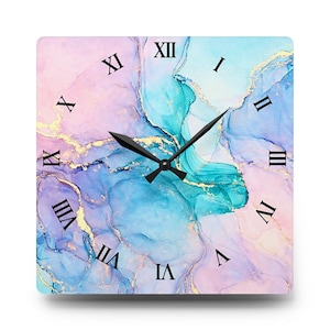 May include: Square wall clock with a colorful abstract design in shades of blue, pink, and gold. The clock face features black Roman numerals and black clock hands. The clock is a decorative item for home decor.