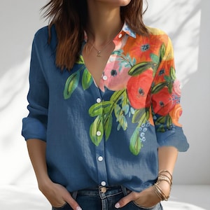 May include: A long-sleeved button-down shirt. The left side is plain blue, and the right side and upper section have a floral pattern in orange, pink, and green. It has a standard collar and white buttons.