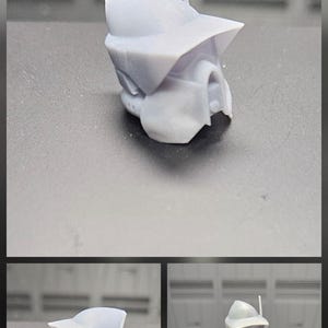 Puede incluir: Un accesorio de casco de resina gris claro sin pintar que presenta una visera ancha y una antena delgada, dise&ntilde;ado para una peque&ntilde;a figura de acci&oacute;n. El casco tiene una forma angular distintiva y se muestra tanto solo como en una figura blanca.