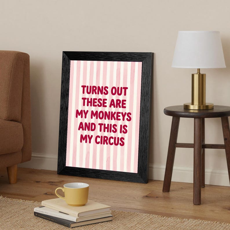 May include: Framed art print with a black border. The print features a pink and white striped background with the text "TURNS OUT THESE ARE MY MONKEYS AND THIS IS MY CIRCUS" in maroon lettering.