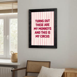 May include: A framed print with the text "TURNS OUT THESE ARE MY MONKEYS AND THIS IS MY CIRCUS" in burgundy letters. The background has vertical pink and white stripes. The frame is black.