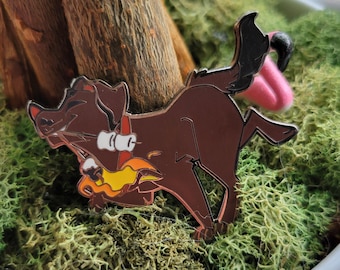 May include: A brown dog enamel pin featuring a canine running while holding a roasting stick with two white marshmallows over a yellow and orange flame. The pin has a dark metal outline and a pink tail detail, capturing a playful camping scene.