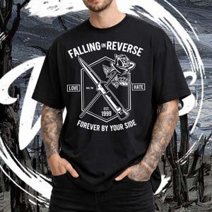 May include: Black t-shirt with the text "FALLING IN REVERSE" and a graphic of a knife and rose. The shirt also includes the text "LOVE", "HATE", "EST. 1999", and "FOREVER BY YOUR SIDE". The shirt is worn by a person.