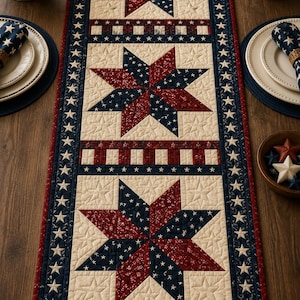 Puede incluir: Un camino de mesa rectangular con un patrón de edredón patriótico que presenta tres grandes estrellas de ocho puntas en rojo, blanco y azul. El borde está decorado con un motivo de estrellas repetitivo y la tela muestra un estampado texturizado.