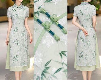 May include: A light green midi dress featuring a mandarin collar, short sleeves, and a side-fastening closure with two spherical buttons. The fabric displays a white floral jacquard pattern overlaid with a green bamboo leaf print design.