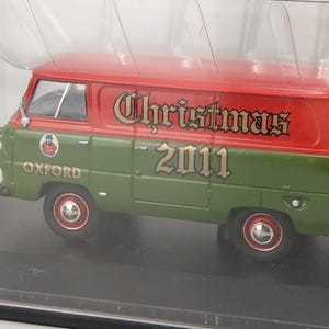 Puede incluir: Una furgoneta en miniatura verde y roja con el texto "Christmas 2011" en el lateral. La furgoneta tiene la palabra "Oxford" en el lateral y ruedas rojas. Es un artículo de colección.