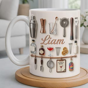 May include: White ceramic mug featuring a collection of bar tools and bottles, with the name "Liam" in a copper script. Includes a cocktail recipe card and a rainbow-colored bottle. The mug sits on a wooden coaster.