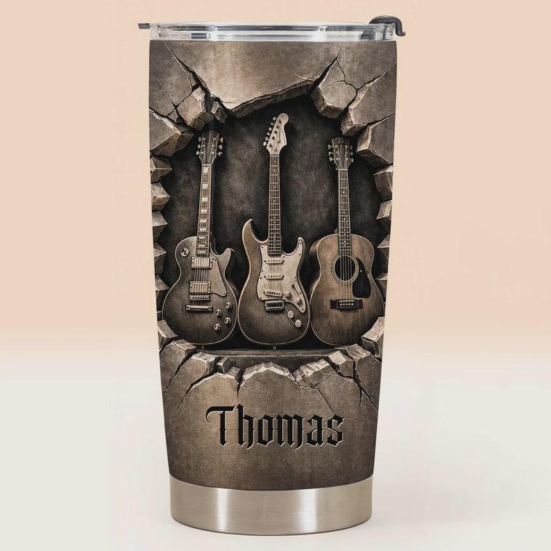 May include: A stainless steel tumbler featuring three guitars emerging from a cracked stone wall design. The name "Thomas" is displayed in a gothic font at the bottom of the tumbler. The guitars are a mix of electric and acoustic styles.