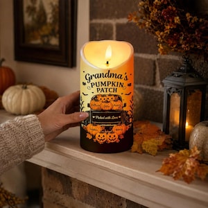 May include: A cylindrical LED candle with a warm glow, featuring the text "Grandma's PUMPKIN PATCH" and "Picked with Love". The design includes a black truck illustration carrying orange pumpkins labeled with names like William and Chloe.