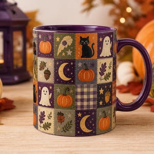 May include: A ceramic mug with a purple interior and handle, featuring a patchwork grid pattern on the exterior. The design includes illustrations of orange pumpkins, black cats, white ghosts, yellow crescent moons, acorns, and autumn leaves.