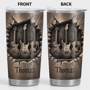May include: Stainless steel tumbler featuring a design of four guitars emerging from a cracked stone background. The name "Thomas" is displayed in a decorative font below the guitars. The front and back of the tumbler are shown.