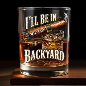 May include: A clear glass tumbler featuring the white text I'LL BE IN THE BACKYARD with the name WILLIAM printed on a brown cigar graphic. The glass contains a smaller illustration of a whiskey glass filled with amber liquid and ice cubes.