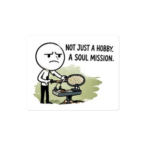 May include: A sticker featuring a cartoon figure with a sad expression operating a waffle iron. The text reads, "NOT JUST A HOBBY. A SOUL MISSION.". The image has a white background and a green and brown color scheme.
