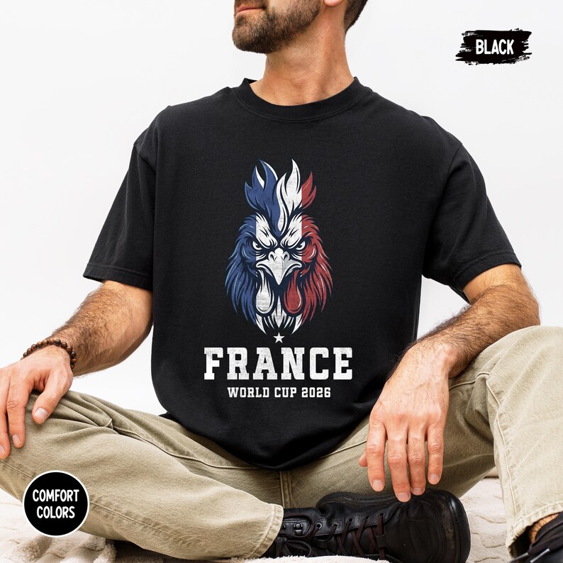 May include: Black t-shirt featuring a rooster design in the colors of the French flag: blue, white, and red. The word "FRANCE" is printed in white, along with "WORLD CUP 2026". The shirt is labeled "BLACK" and "COMFORT COLORS".