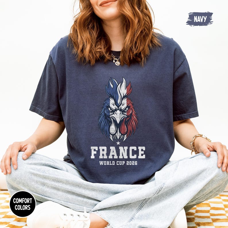 May include: Navy blue t-shirt featuring a stylized rooster in the colors of the French flag. The text "FRANCE WORLD CUP 2026" is printed below the rooster. The shirt is a comfort colors style.