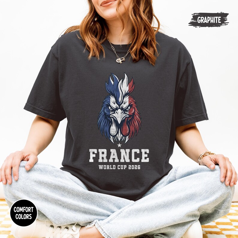 May include: Graphite-colored t-shirt featuring a detailed illustration of a rooster in the colors of the French flag. The text "FRANCE WORLD CUP 2026" is printed below the rooster. The shirt is part of the Comfort Colors collection.