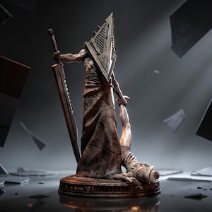 May include: A detailed statue of a figure with a pyramid-shaped head, holding a large sword and a smaller figure. The statue is primarily brown with a textured appearance, set on a circular base. The background is dark with scattered debris.
