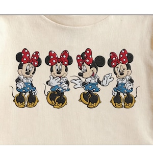 May include: Embroidered design featuring four Minnie Mouse figures. Each figure has a red polka-dot bow, white gloves, a blue polka-dot skirt, and yellow shoes. The design is on a cream-colored fabric.