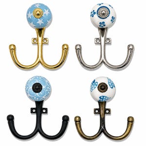 May include: Four double wall hooks with ceramic knobs. The top left has a light blue knob with white stars and a gold finish. The top right has a white knob with blue flowers and a silver finish. The bottom left has a light blue knob with white patterns and a black finish. The bottom right has a white knob with blue hearts and an antique brass finish.