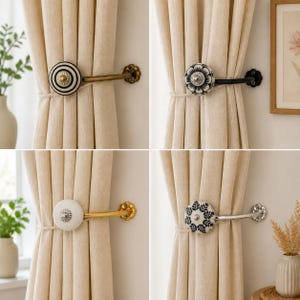 May include: Four curtain tiebacks featuring decorative knobs in various patterns and finishes. The knobs include black and white stripes, floral motifs, and solid white, attached to metal arms in brass, black, gold, and silver tones.