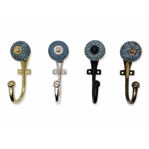 May include: Four wall hooks with decorative ceramic knobs. The first has a gold finish and blue floral knob, the second a silver finish and blue ridged knob, the third a black finish and blue geometric knob, and the fourth a bronze finish and blue floral knob.