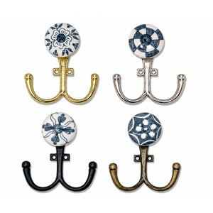 Peut inclure: Quatre patères doubles avec des boutons en céramique ronds ornés de motifs bleus et blancs. Les crochets présentent différentes finitions métalliques : or poli, argent, noir mat et laiton antique. Chaque patère possède deux bras courbés.