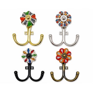 May include: A set of four double wall hooks featuring decorative ceramic flower knobs. Each hook has a unique metal finish including polished gold, silver, matte black, and antique brass, with colourful hand-painted floral patterns on the knobs.