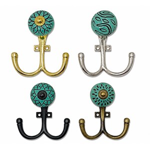 May include: Four double-pronged wall hooks featuring decorative ceramic knobs in shades of teal and turquoise. The hooks come in polished gold, silver, matte black, and antique brass finishes, each with unique geometric or floral patterns on the knobs.