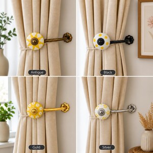 Puede incluir: Cuatro alzapaños para cortinas con pomos de cerámica redondos con motivos florales amarillos y blancos. Los brazos metálicos tienen acabados en antiguo, negro, dorado y plateado, con un soporte de pared en forma de flor para cortinas beige.
