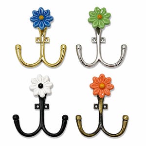 May include: A set of four double-pronged wall hooks, each topped with a ceramic flower. The hooks feature metallic finishes in gold, silver, matte black, and antique bronze, paired with blue, green, white, and orange floral accents respectively.